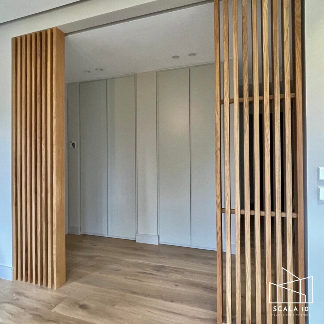 Revestimiento en madera en la entrada de una habitación, con puertas correderas y paredes blancas.