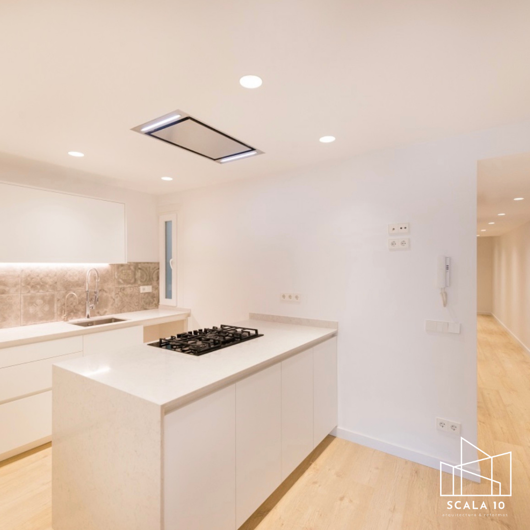 Cocina moderna con isla central, estufa de gas, fregadero y vestigios de azulejos decorativos en la pared.