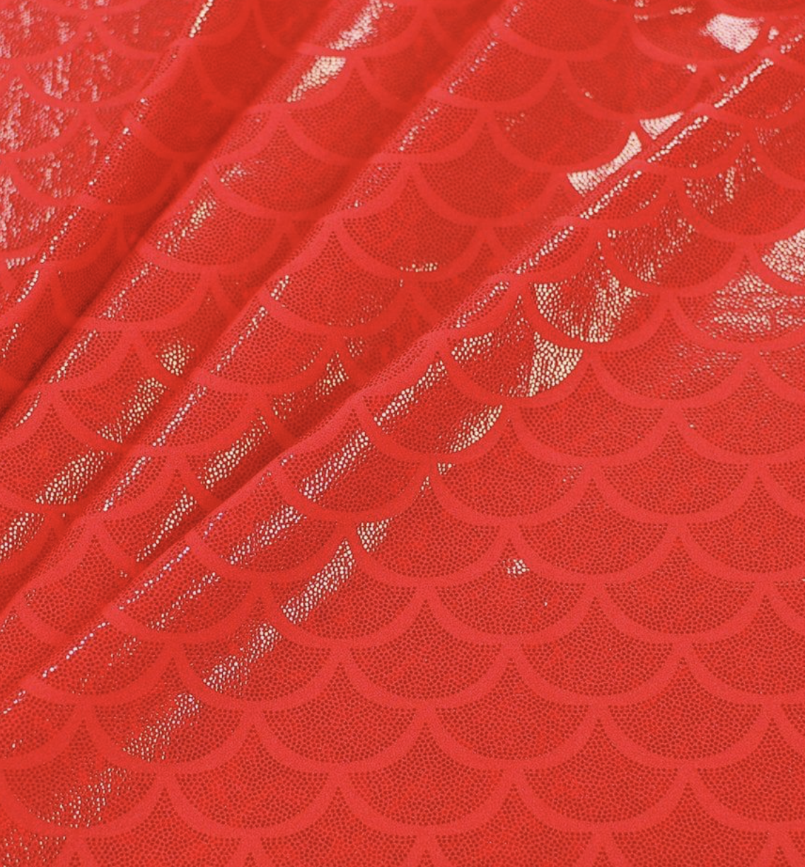 Close-up of red fabric with a pattern of shimmering scale-like shapes.