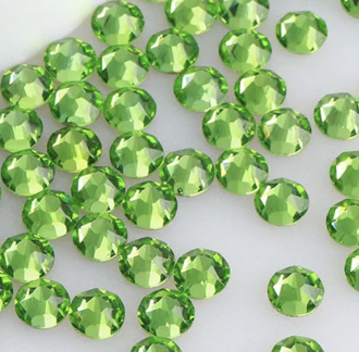 Array of bright green faceted gemstones scattered on a white background.