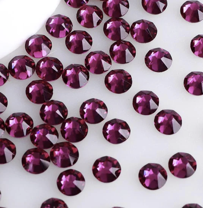 Numerous purple rhinestones scattered on a white surface