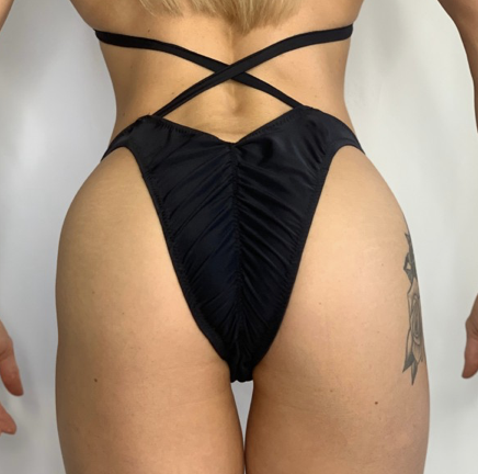 Close-up of a woman's lower body wearing black bikini bottoms with crisscross straps.
