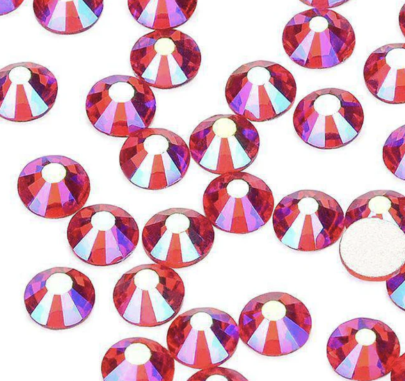 Multiple red, iridescent rhinestones scattered on a white background.