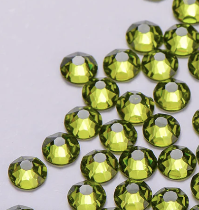 Close-up of green rhinestones scattered on a white surface.