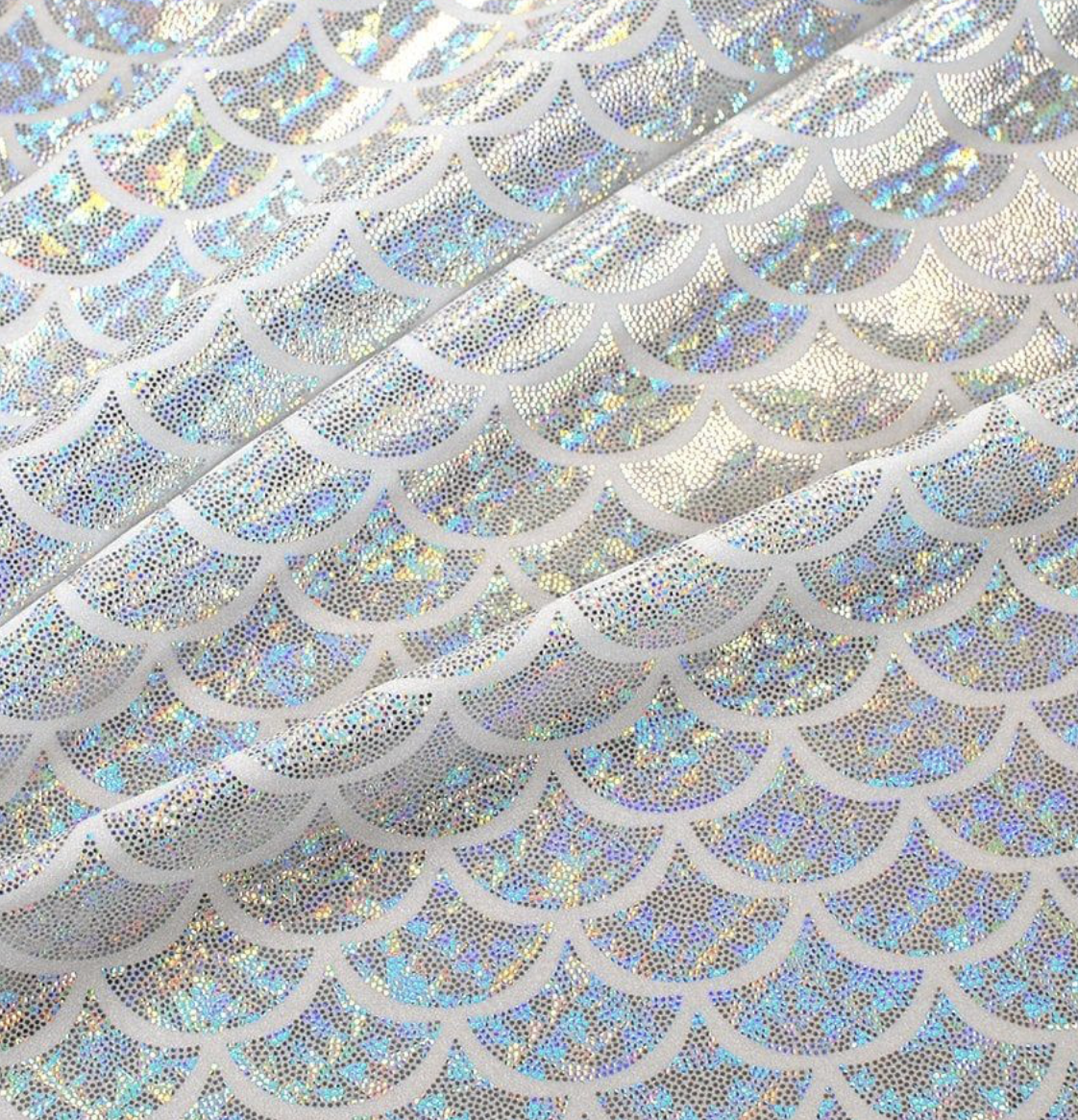 Close-up of holographic paper with a pattern of semi-circular shapes filled with iridescent dots.