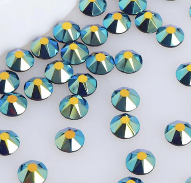 Multiple round, faceted rhinestones with a blue, green, and yellow color scheme scattered on a white surface.
