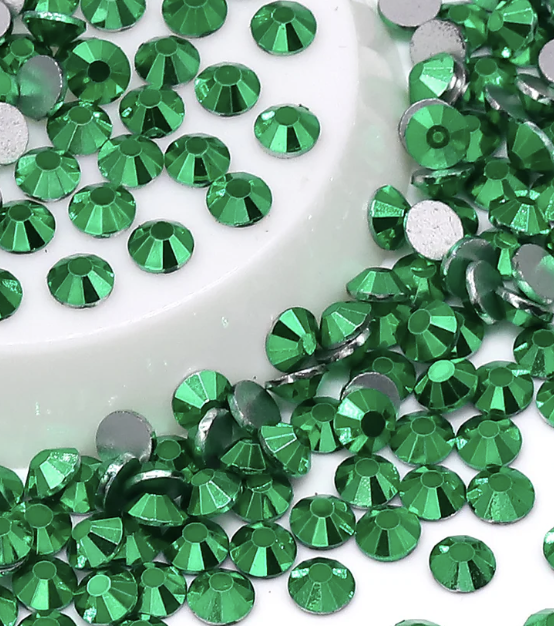 Green and silver rhinestones scattered on a white surface.