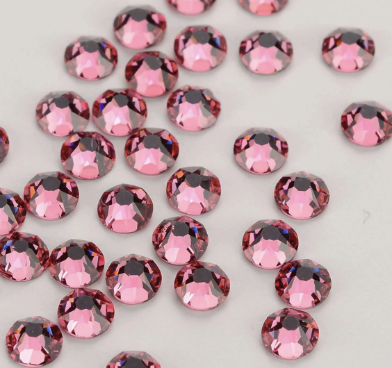 Multiple pink rhinestones scattered on a white surface.