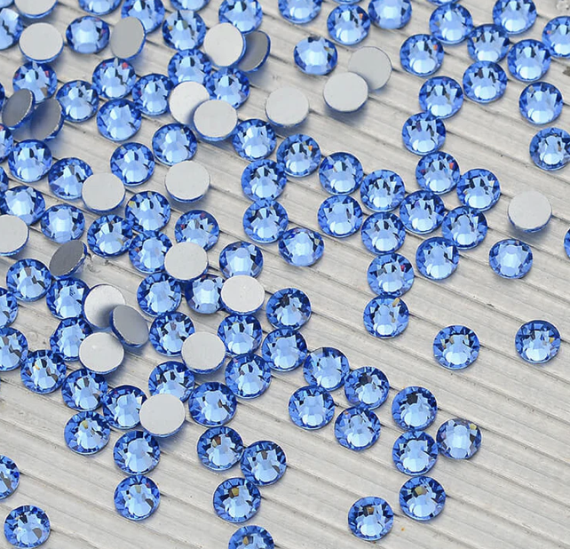 Blue rhinestones scattered on a light wooden surface.