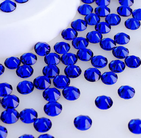 Blue rhinestones scattered on a white surface.