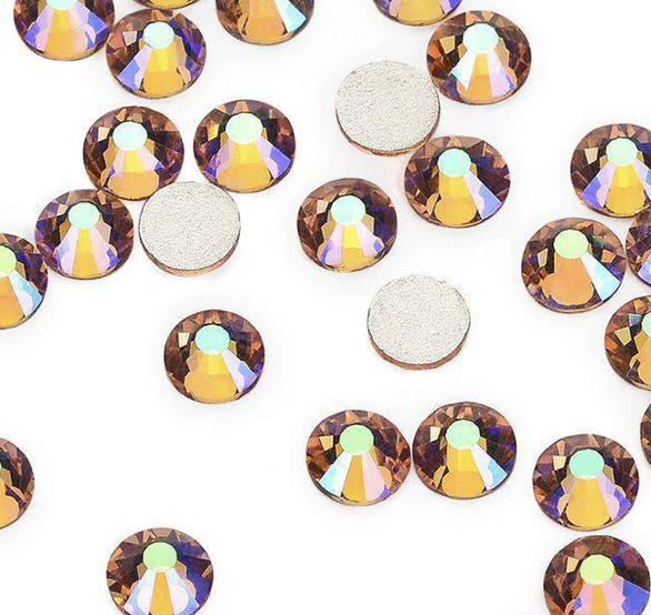 Small, round, iridescent rhinestones with a flat back scattered on a white surface.