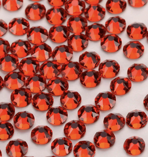 A collection of red faceted rhinestones scattered on a white surface.