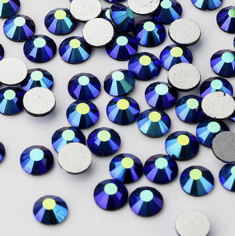 A collection of small, round, faceted blue and yellow rhinestones with flat silver backings on a white surface.