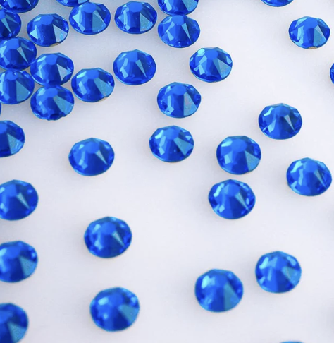 Blue rhinestones scattered on a white surface.