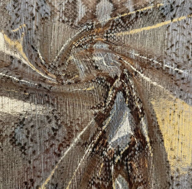 Close-up of a textured fabric with a swirling pattern in brown, beige, black, and gold tones.