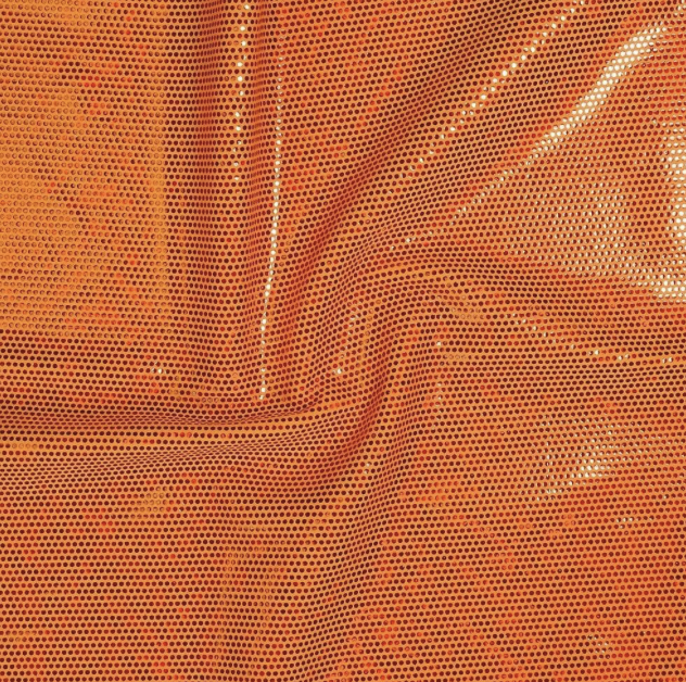 Close-up of an orange fabric with a dotted pattern and some folds.