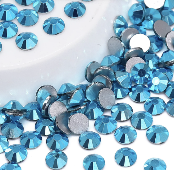 Blue rhinestones with flat silver backs scattered on a white surface.