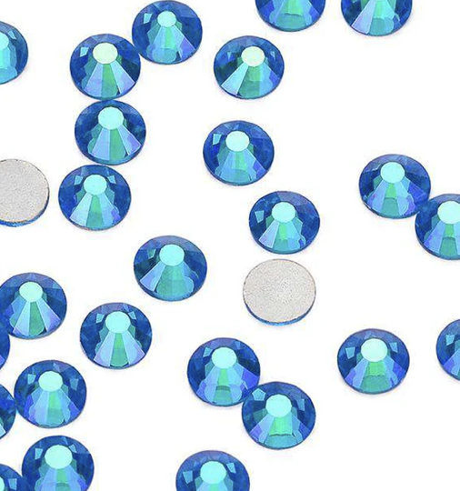 Blue iridescent rhinestones scattered on a white background.