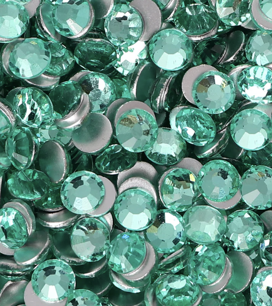 A collection of green rhinestones or gems, many with a faceted surface that reflects light.