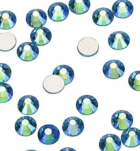 Close-up view of small, round, iridescent rhinestones scattered on a white surface, with some missing.