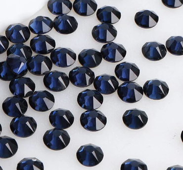 Collection of dark blue gemstones with facets on a white background.