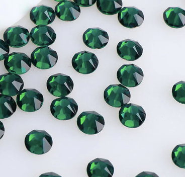 Collection of small, round, green gemstones scattered on a white surface.