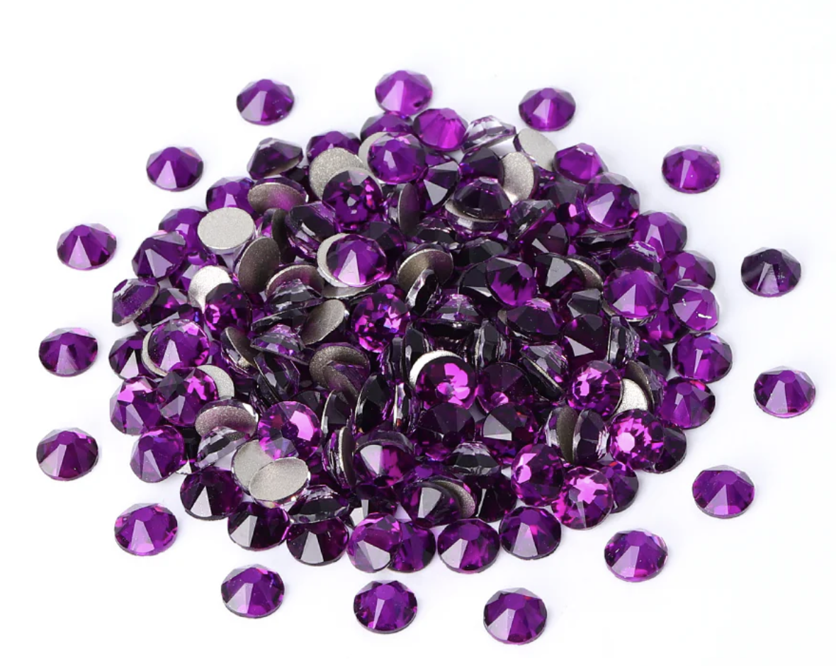 A pile of purple rhinestones on a white background.