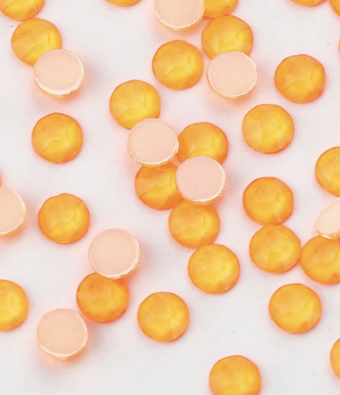 Scattered round candies with orange and white colors on a white background.