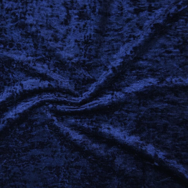 Close-up of dark blue velvet fabric with a gathered wrinkle in the center.