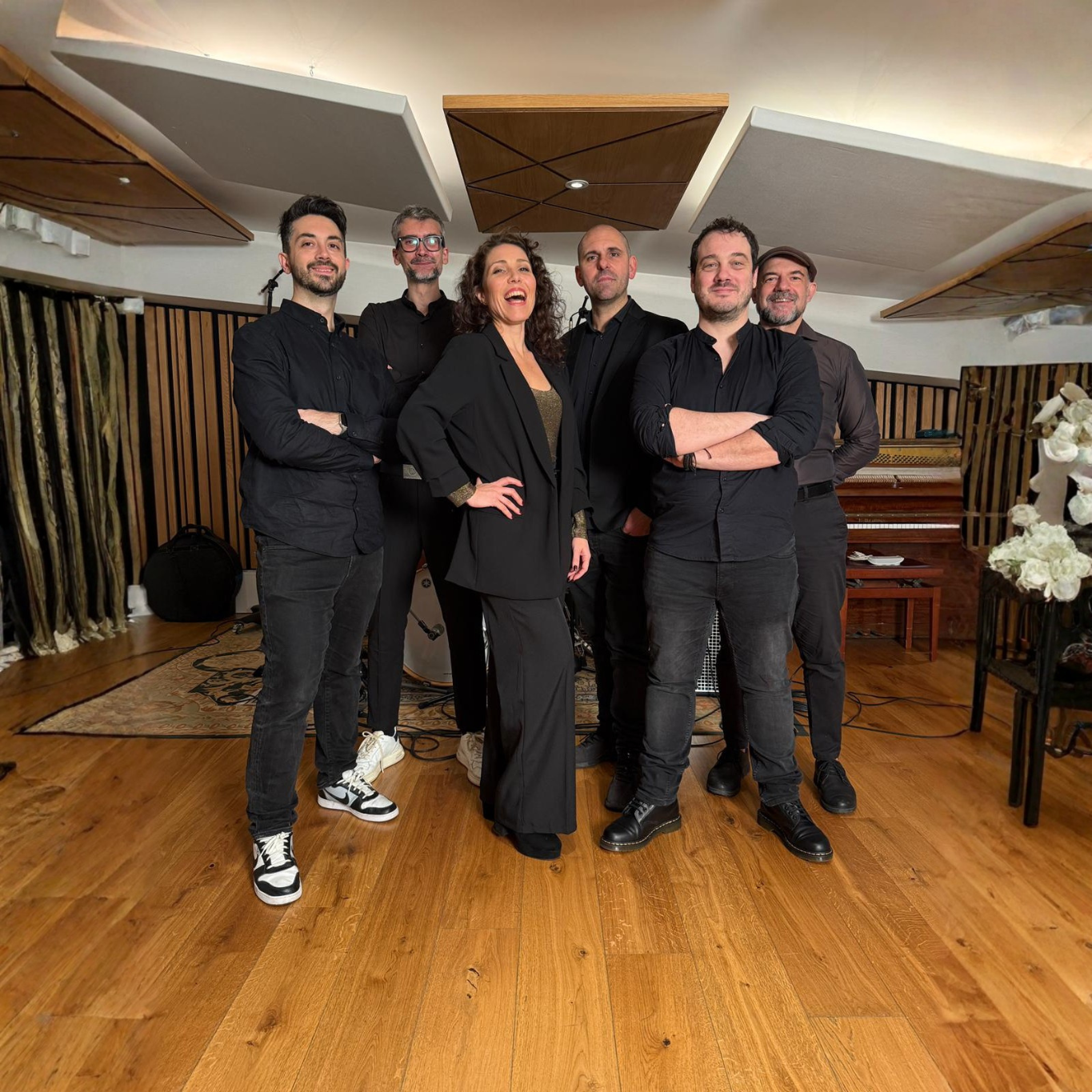 Group of six people standing in a music studio, smiling and posing for a photo.