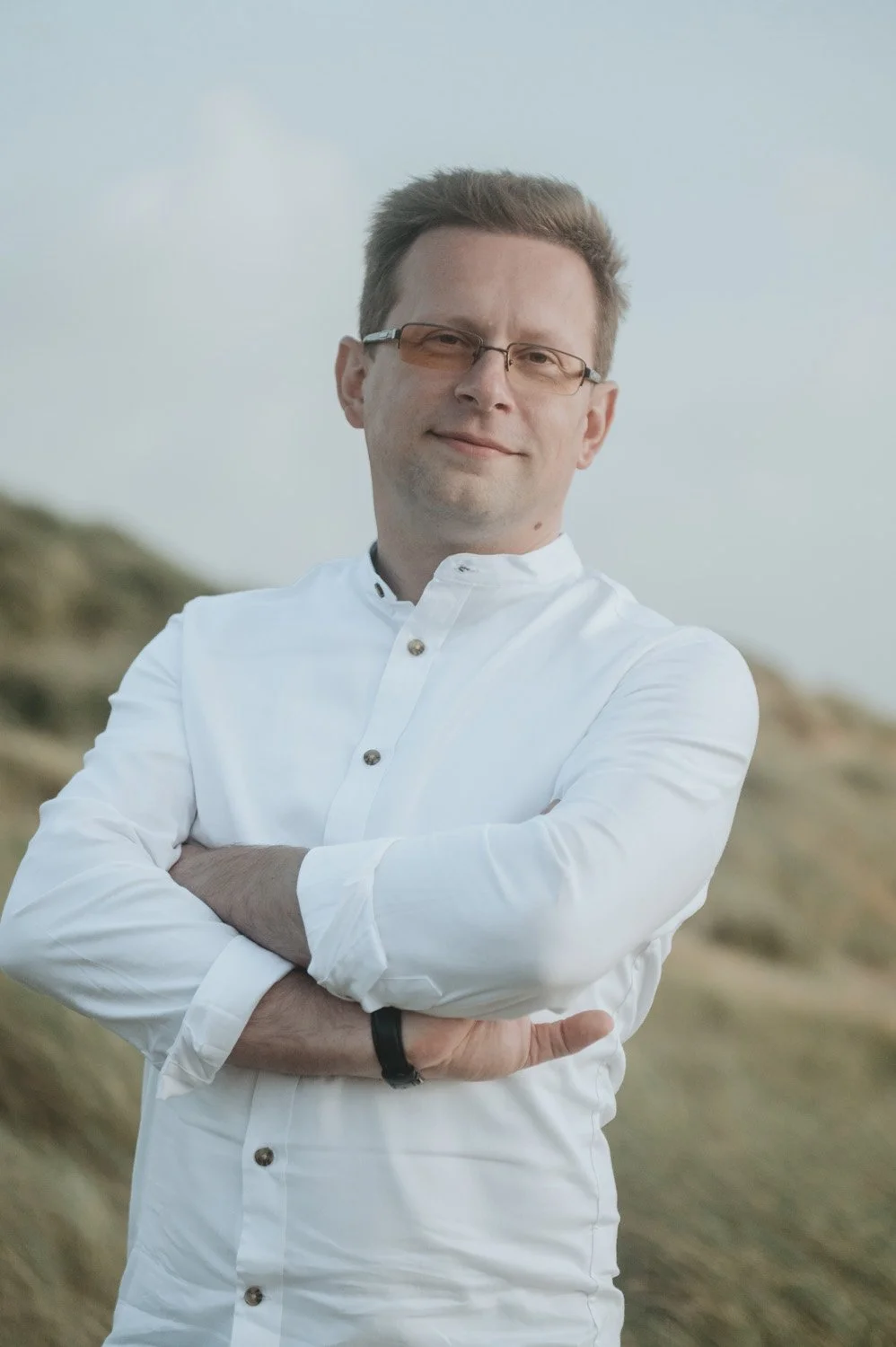 Jurij Blazejewski standing outdoors with a landscape of hills in the background.