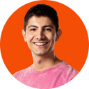 Smiling young man with dark hair and eyebrows, wearing a pink shirt, against an orange background.