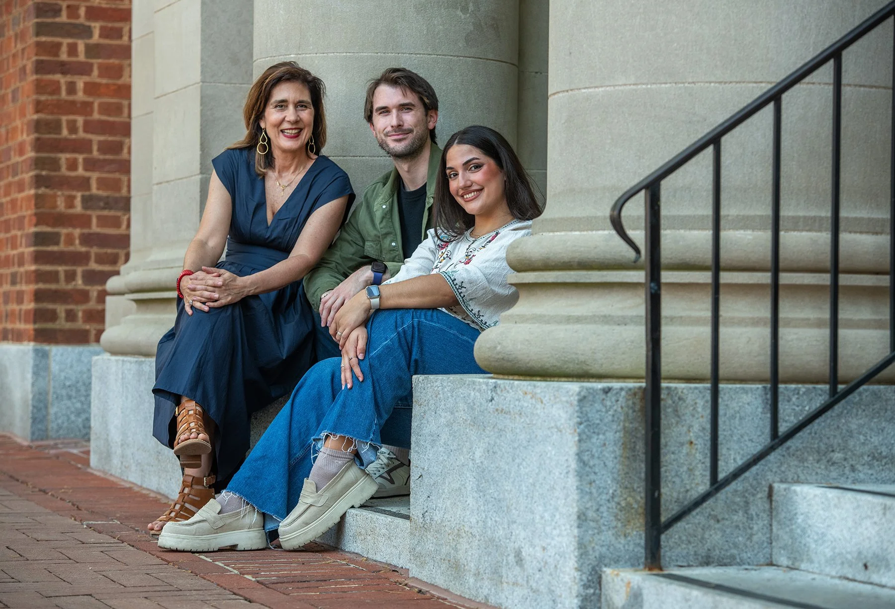 Three people smiling on stone steps.