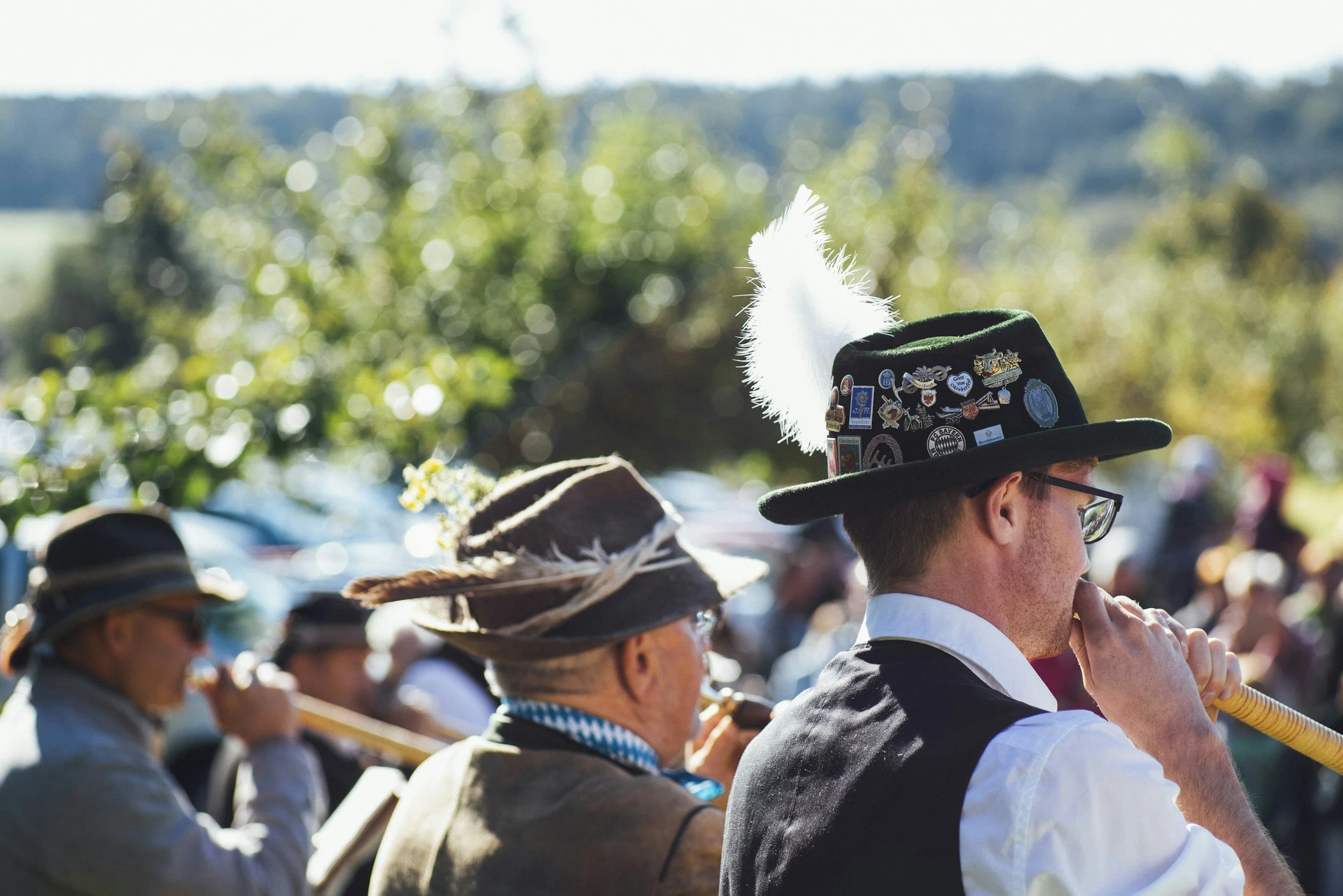 Musicians in traditional Bavarian costumes playing flutes outdoors at a festival or gathering.