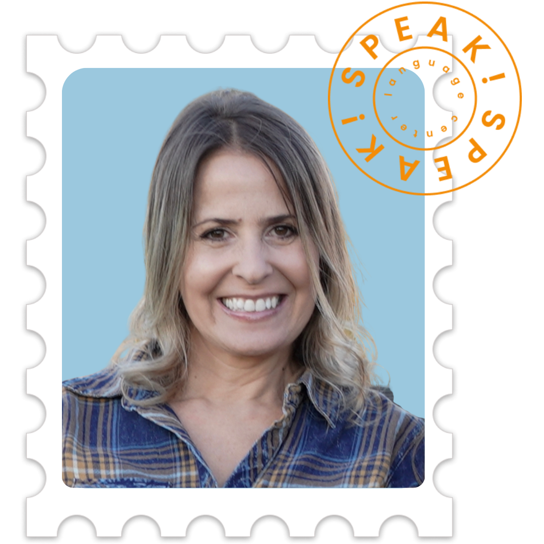 A smiling woman with shoulder-length blonde hair in front of a light blue background, wearing a plaid shirt.