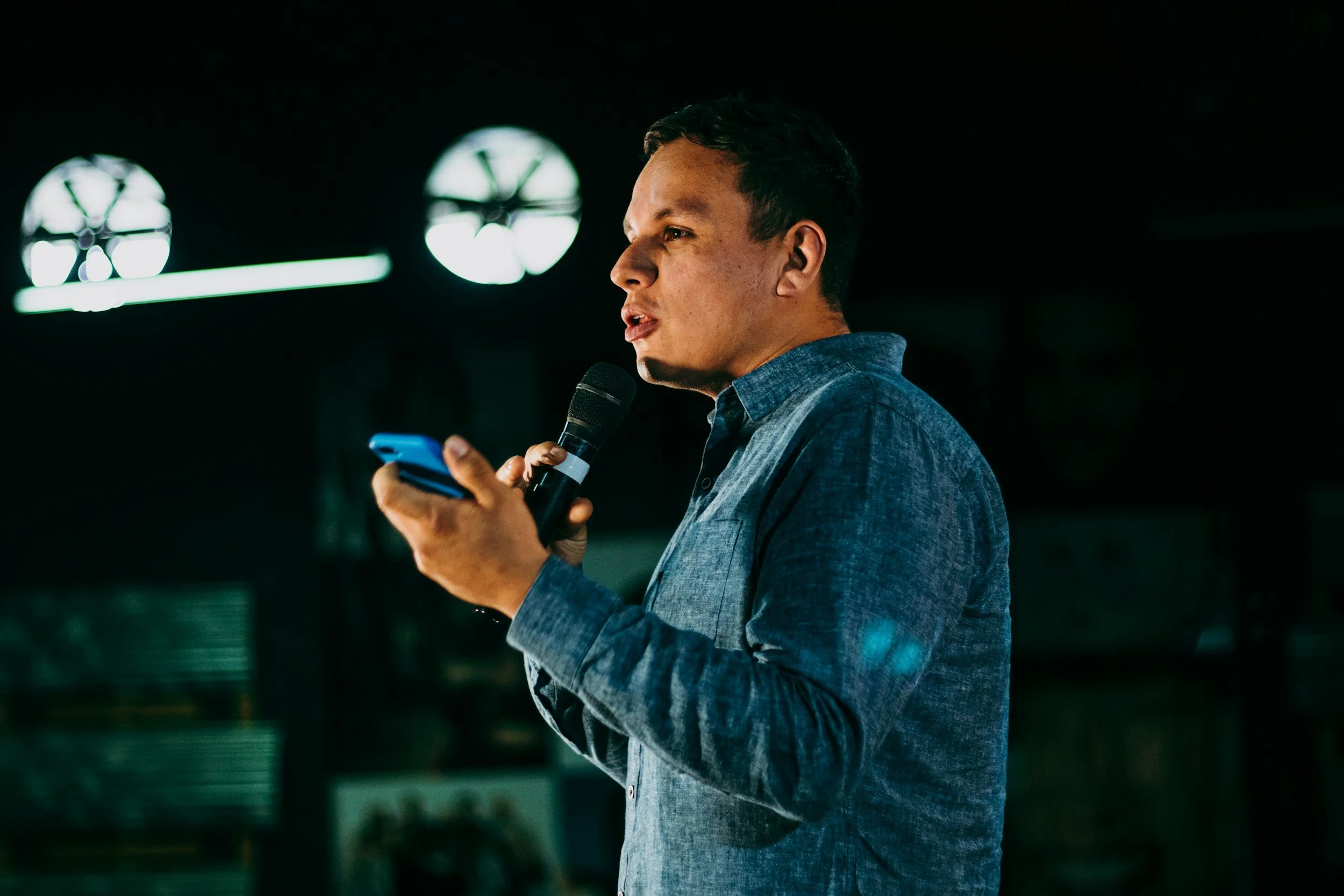 A man speaking into a microphone while holding his phone.