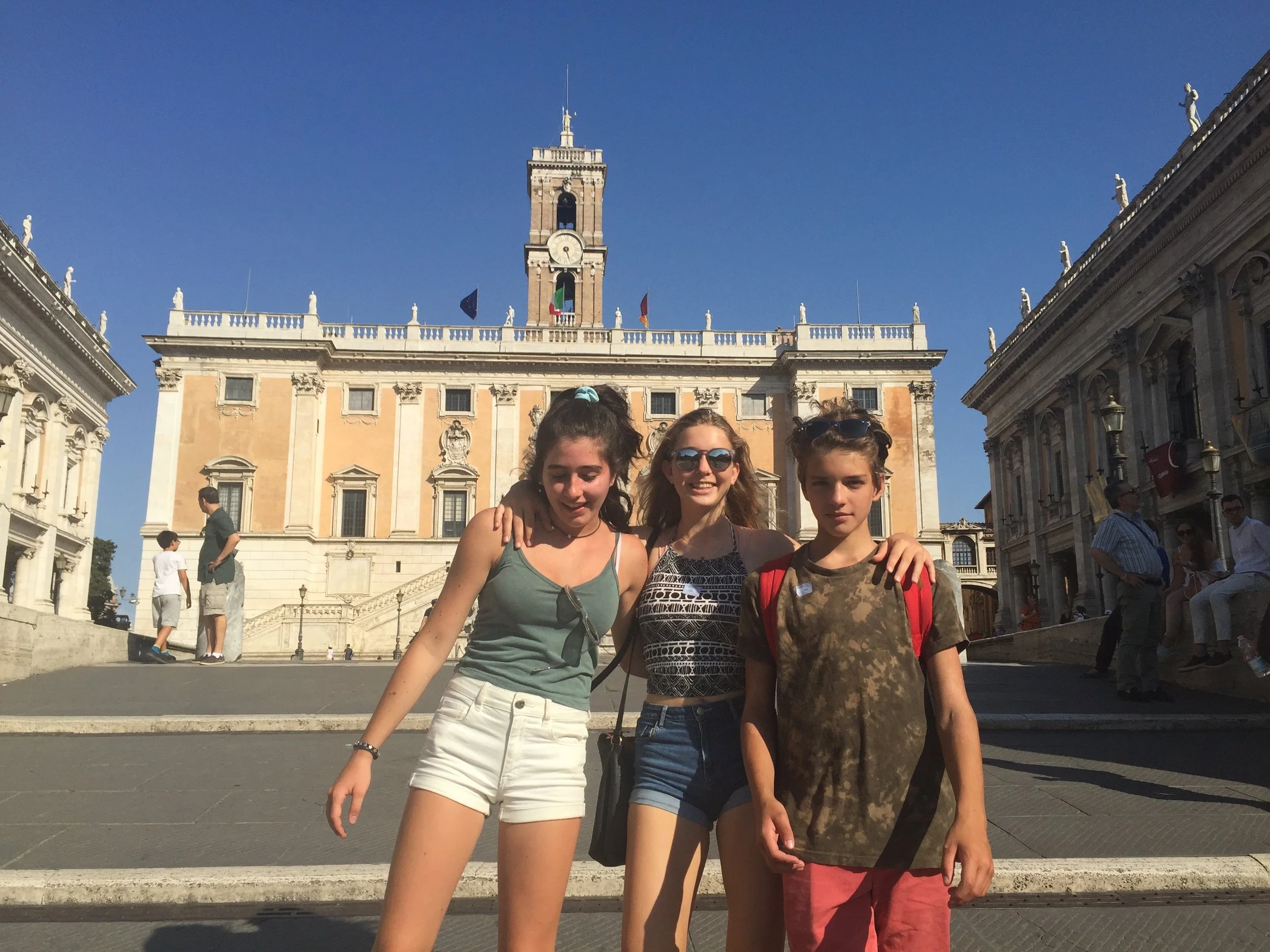 Three people posing together in a historic city square.