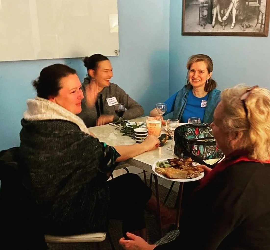Four women laughing and talking around a table.