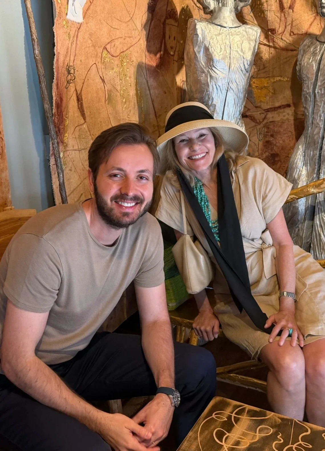 A man and woman smiling together in front of artwork.