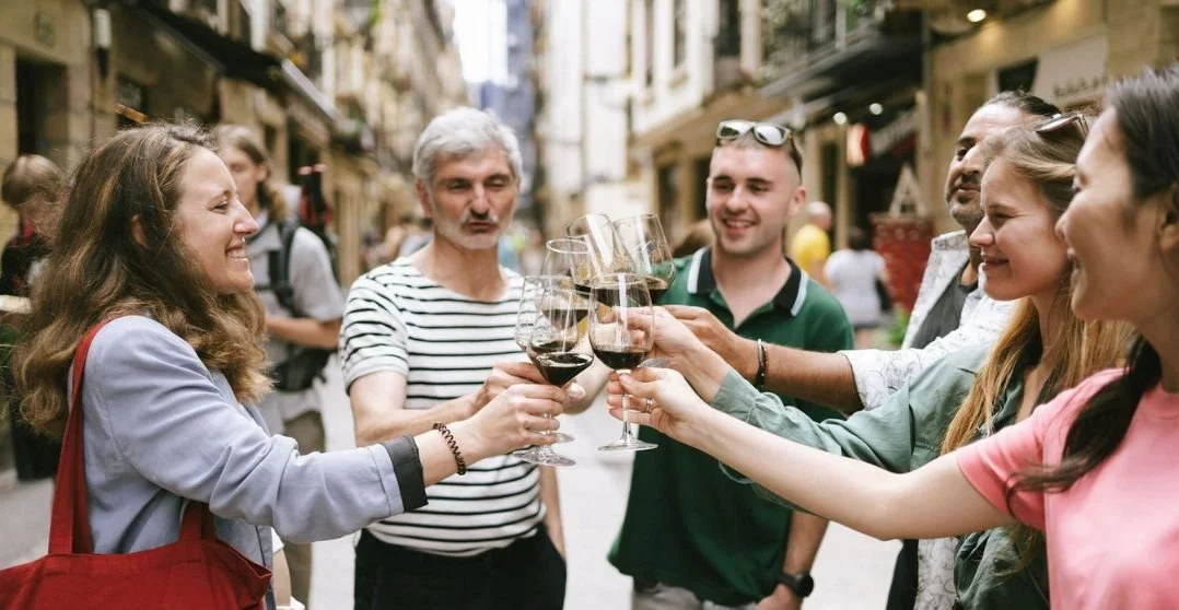 Group of friends raising glasses of wine for a toast on a crowded city street.