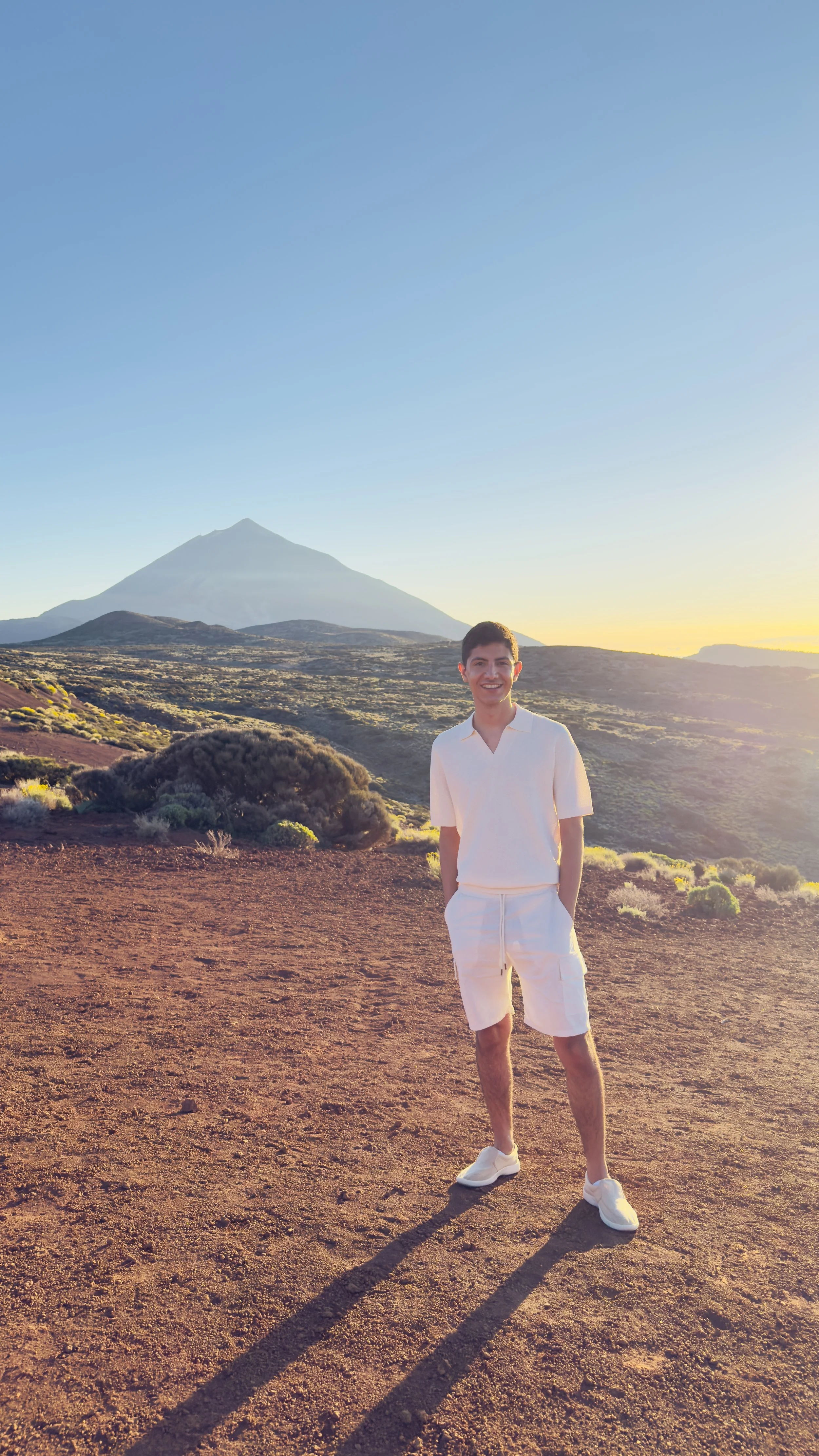 A man overlooking a landscape of hills at sunset.