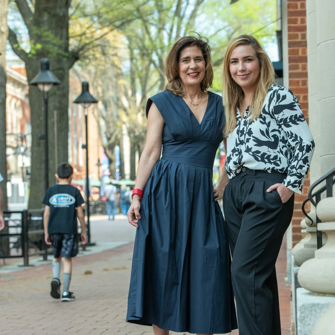 Two women smiling on a sidewalk.