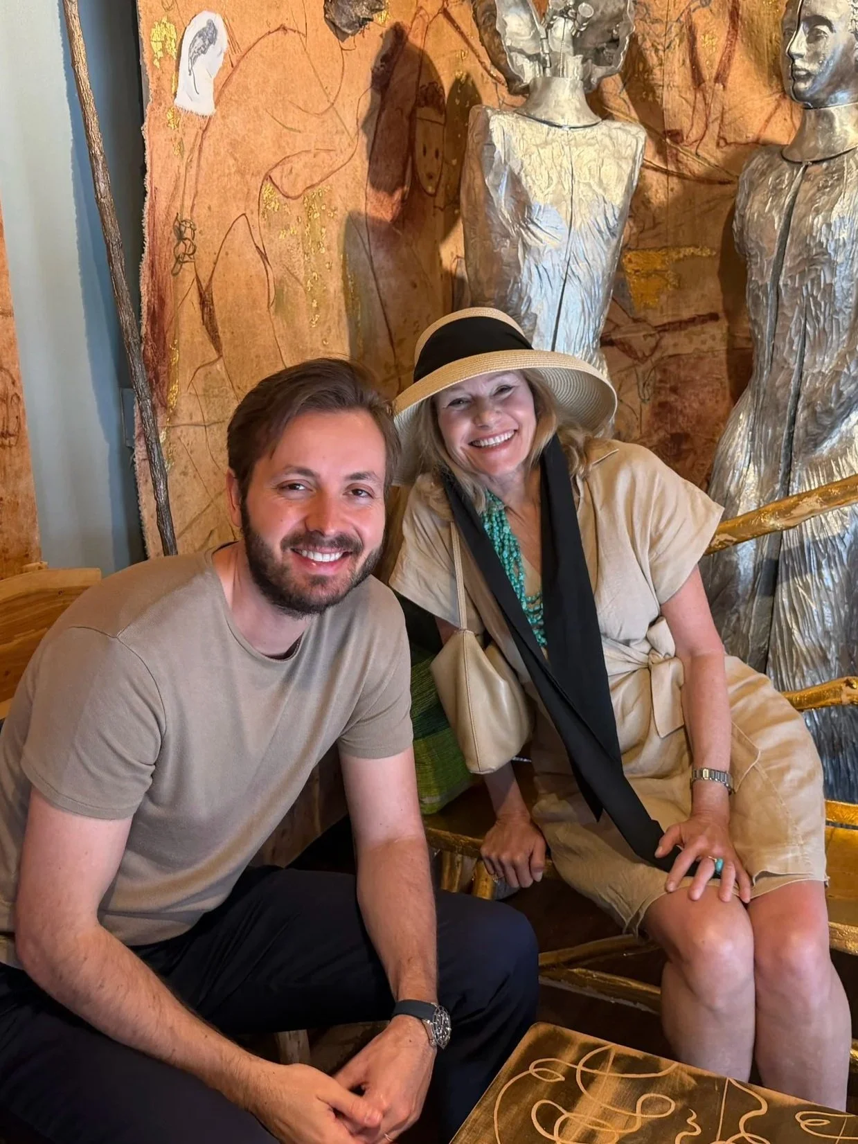 Two people seated together in front of artwork.