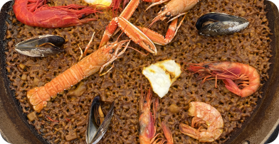 Seafood paella with lobster, shrimp, mussels, and rice in a paella pan.