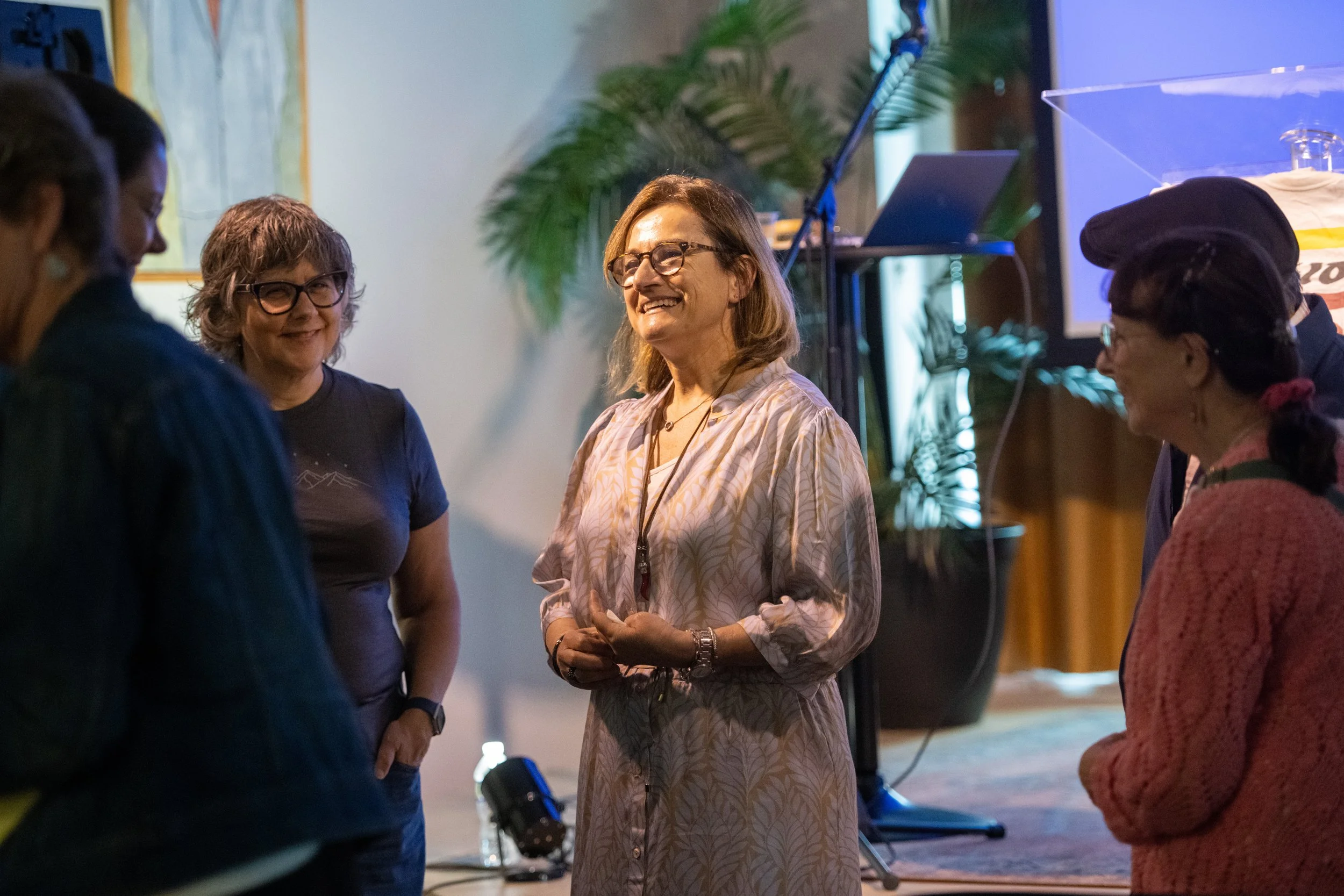 A woman speaking with a group at an indoor event.