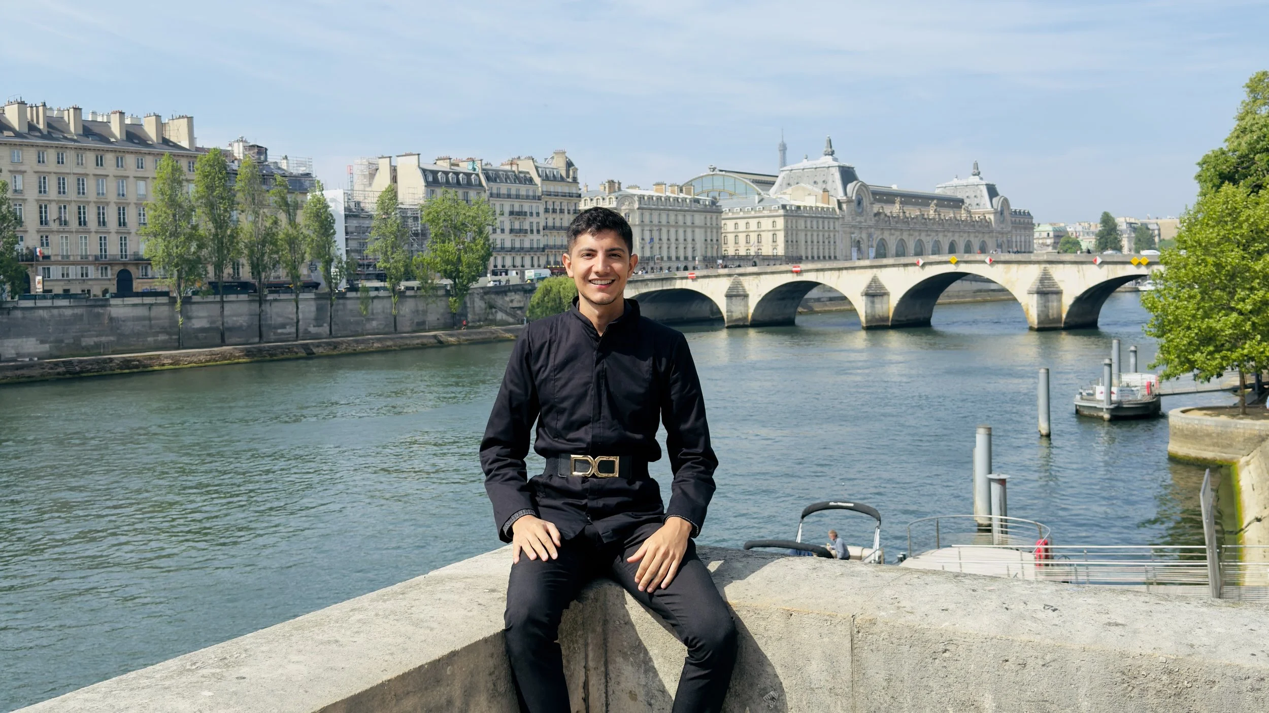 A man seated beside a river in Paris.