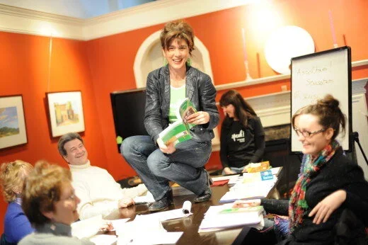 A woman holding a book during a group discussion.
