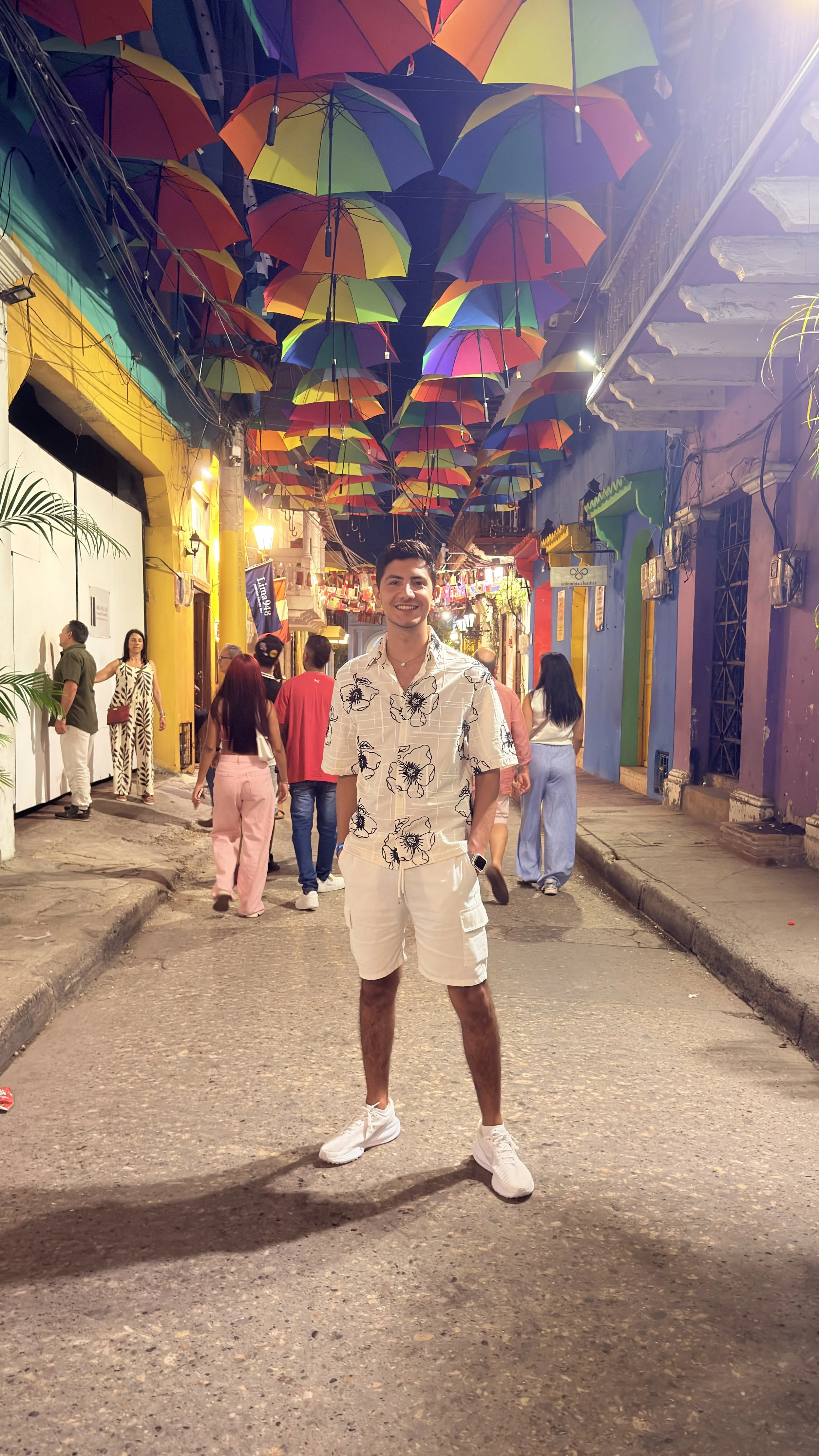 A man on a street decorated with colorful umbrellas.