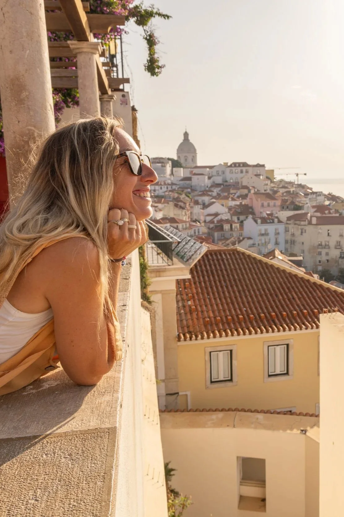 A woman looking across a city from a terrace at sunset.