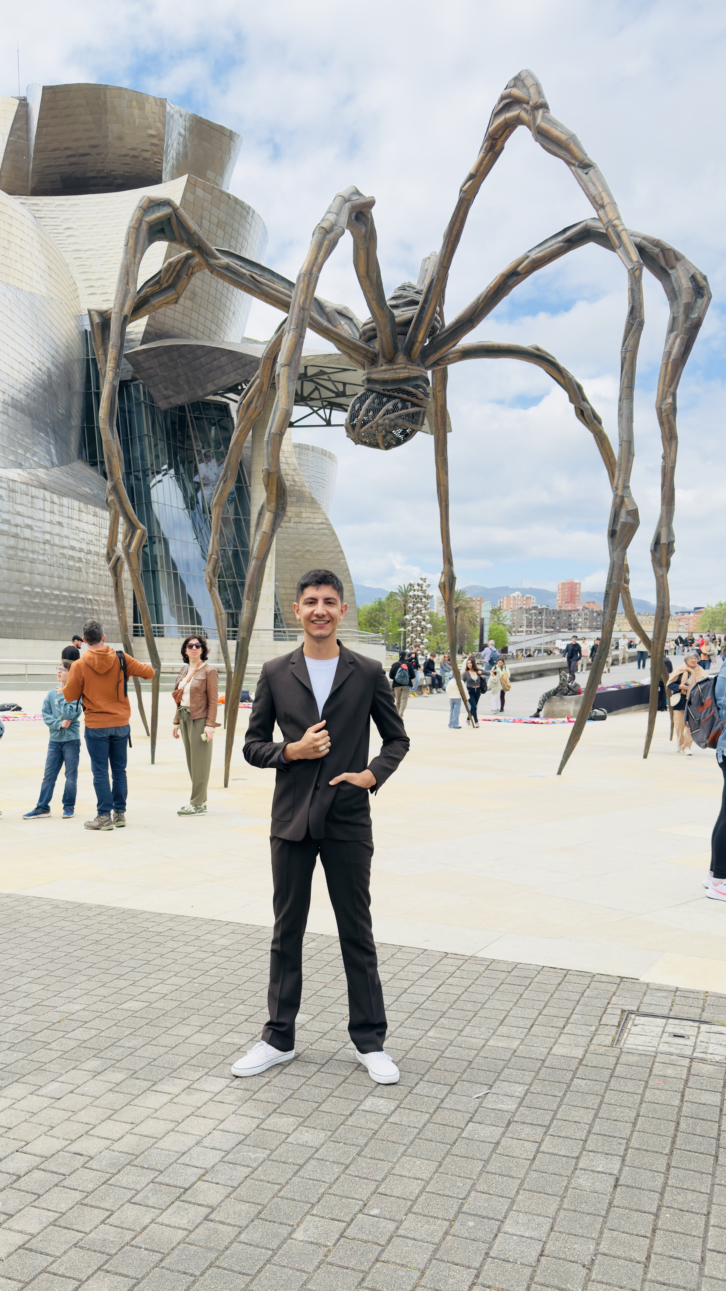 A man standing beside a large spider sculpture.